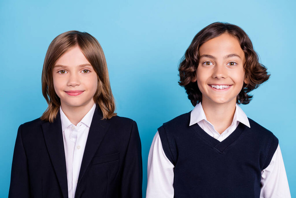Photo portrait two school mates smiling in uniform sitting on lesson isolated pastel blue color background - Foto, Bild