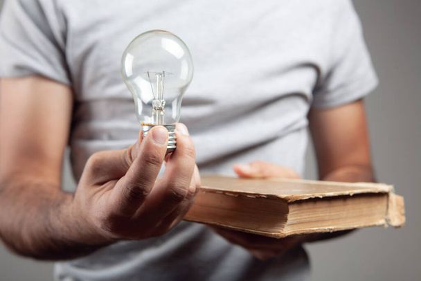 Egy férfi nyitott könyvvel és villanykörtével. koncepció ötlet egy könyvből - Fotó, kép