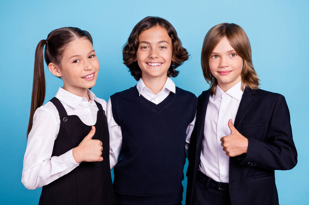 Photo of funny shiny schoolchildren wear uniform hugging embracing showing thumbs up smiling isolated blue color background - Foto, Bild
