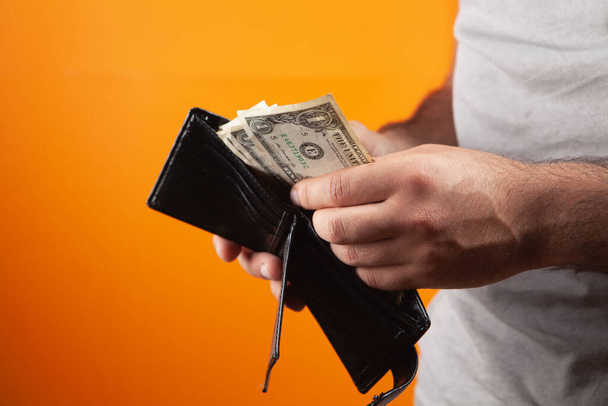 a man pulls out money from a wallet on an orange background - Foto, Imagem