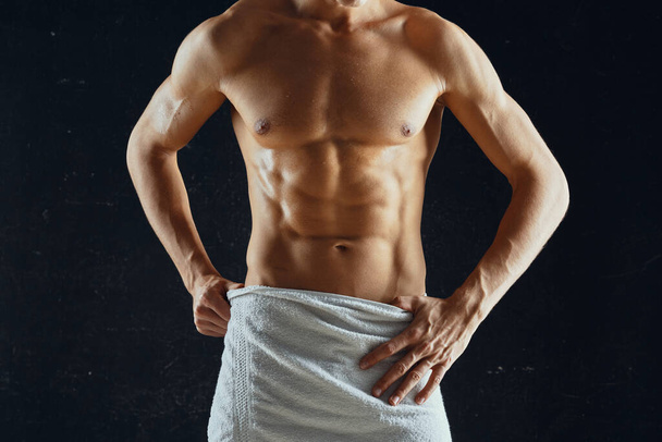 σπορ άνθρωπος με ένα φουσκωμένο μυϊκό σώμα σε μια πετσέτα σκούρο φόντο - Φωτογραφία, εικόνα