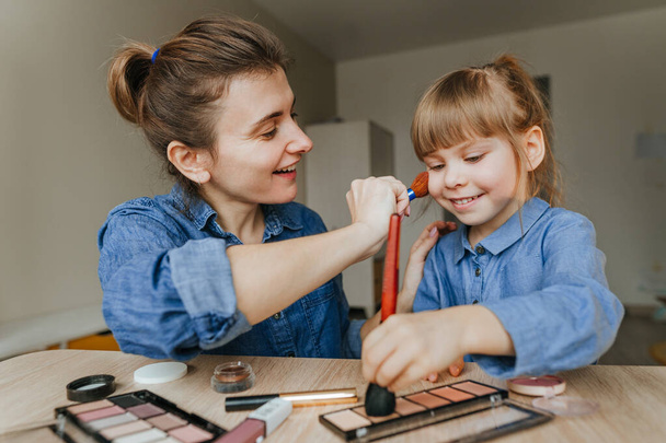 Portrait of young mother and her little daughter making make up each other - Photo, Image