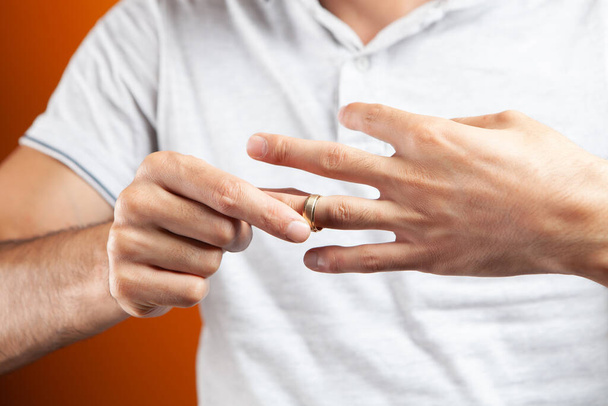 een man doet een ring om zijn vinger op een oranje backgroun - Foto, afbeelding