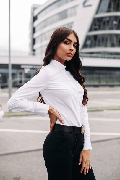Beautiful brunette posing against the background of a modern building - Фото, зображення