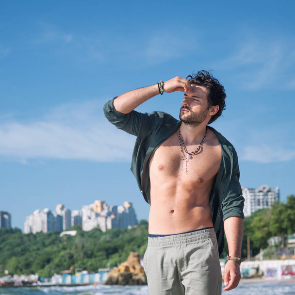 Young man sexy topless outdoor portrait near the ocean in big city - Fotó, kép