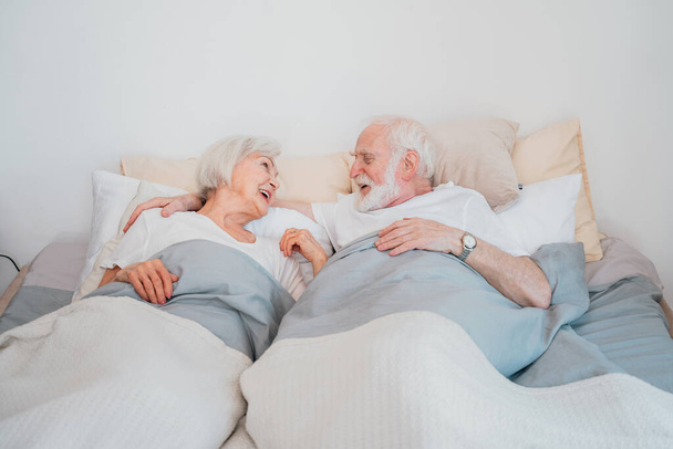 Beautiful senior couple enjoying time together at home - Romantic moments at home, elderly couple in bed at home - 写真・画像