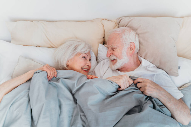 Beautiful senior couple enjoying time together at home - Romantic moments at home, elderly couple in bed at home - Fotó, kép