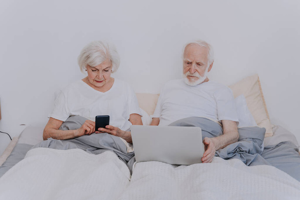 Beau couple de personnes âgées profiter du temps ensemble à la maison - Moder couple de personnes âgées surfer sur Internet sur ordinateur portable - Photo, image