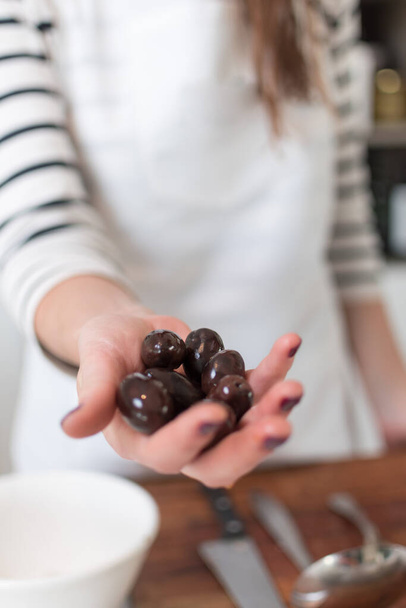 A closeup shot of a female hand full of black olives, pizza making process - 写真・画像