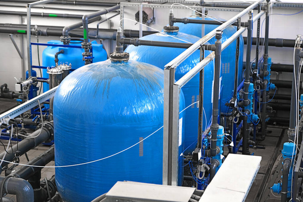 τρεις μεγάλες μπλε δεξαμενές νερού μέσα σε εγκατάσταση επεξεργασίας λυμάτων με πολλούς σωλήνες και αισθητήρες, βιομηχανικό εσωτερικό, εργοστάσιο νερού    - Φωτογραφία, εικόνα