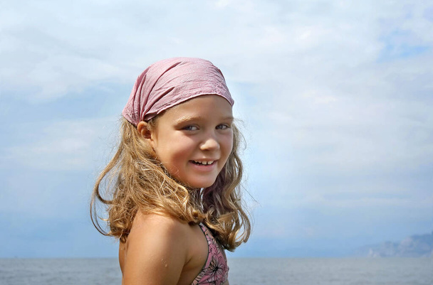 Πορτρέτο του όμορφου μικρού κοριτσιού στο φόντο της θάλασσας, καλοκαιρινή σκηνή. - Φωτογραφία, εικόνα