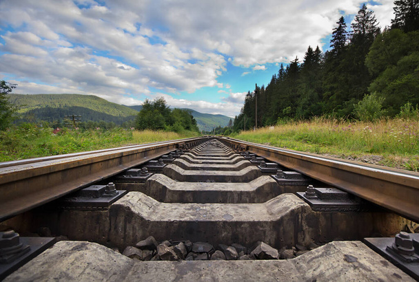 Eisenbahn in die Ferne Gegen Berge und schönen wolkenverhangenen Himmel, Waldnähe. Landschaft mit Eisenbahn. Ansicht von unten. - Foto, Bild