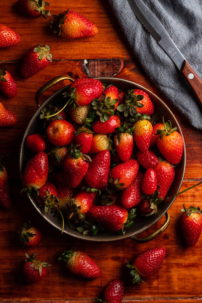 An overhead shot of fresh ripe strawberries on a wooden table - Foto, Imagen