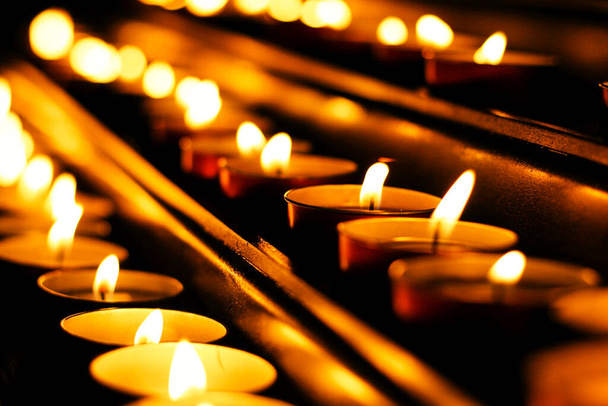 velas encendidas en fila, detalle de la zona de peticiones de la iglesia, iluminar la oscuridad - Foto, Imagen