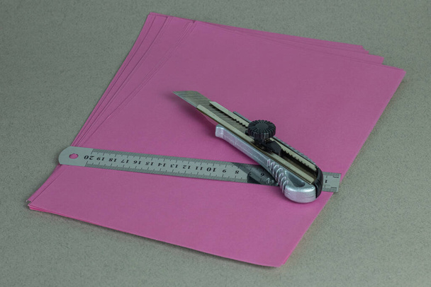 Канцелярський ніж на кольоровому папері разом з вимірювальним лінійкою
 - Фото, зображення