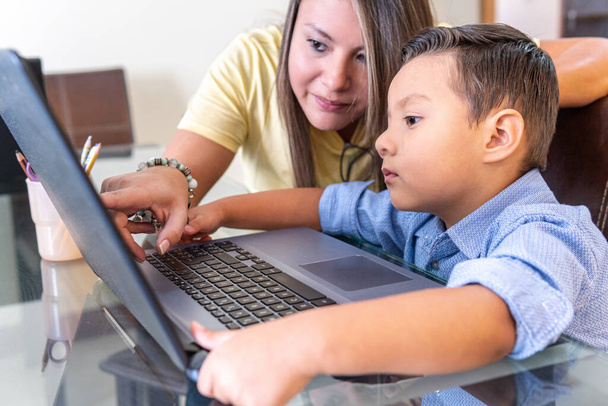 A latin mother helping her son with a school assignment on a laptop at home - Photo, Image