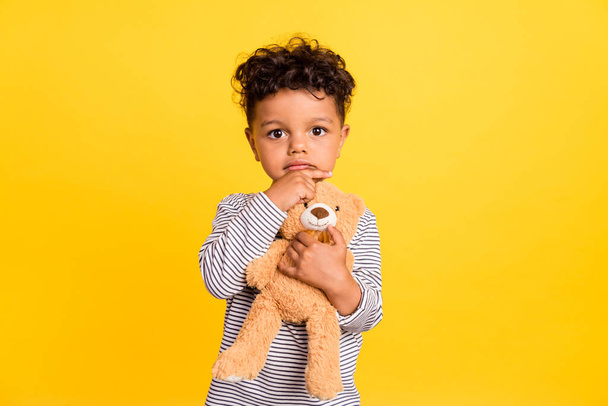 Photo portrait small boy cute hugging soft teddy bear thoughtful isolated vibrant yellow color background - Fotografie, Obrázek
