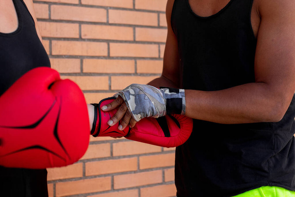 A shallow focus of a Hispanic boxer helping his student to put on the gloves during the practice - Foto, Imagem