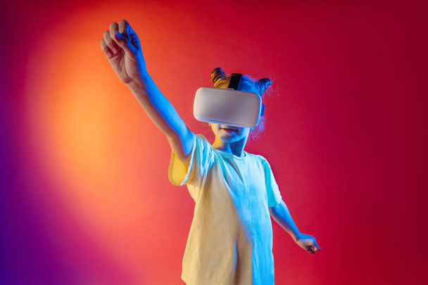 Симпатичная девочка-подросток в виртуальных очках на цветном неоновом фоне с пустым местом для текста. - Фото, изображение