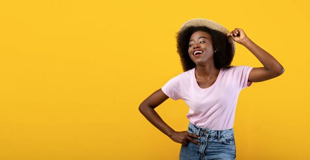 Vibras de verano. Mujer afroamericana feliz en ropa casual y sombrero de paja, fondo amarillo, panorama con espacio libre - Foto, imagen
