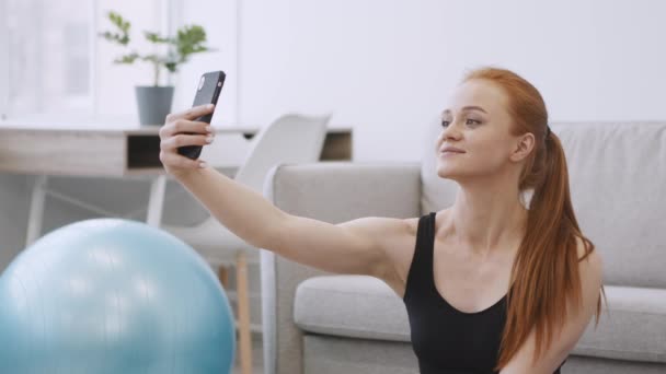 Urheilullinen nainen tekee selfie älypuhelimella harjoittelun aikana kotona - Materiaali, video