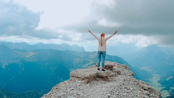 Młoda kobieta z wyciągniętymi ramionami ciesząca się pięknem natury na skale górskiej - Zdjęcie, obraz