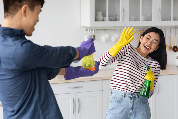 Игривые азиатские любовники веселятся, убирая дом вместе - Фото, изображение