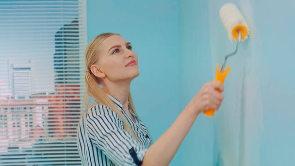 Close-up shot of woman builder painting wall. - Photo, Image
