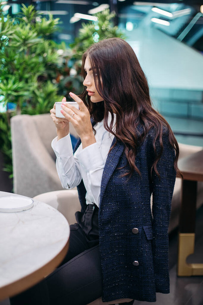 Hezká mladá žena pije horkou kávu v kavárně před tvrdým pracovním dnem - Fotografie, Obrázek