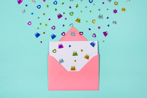 Pinkfarbener Umschlag mit Party-Konfetti-Explosion auf blauem oder türkisfarbenem Hintergrund. Einladungskarte, flach gelegt. - Foto, Bild