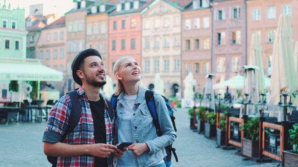 Молодая пара туристов, пользующихся смартфоном и любующихся красивыми окрестностями - Фото, изображение