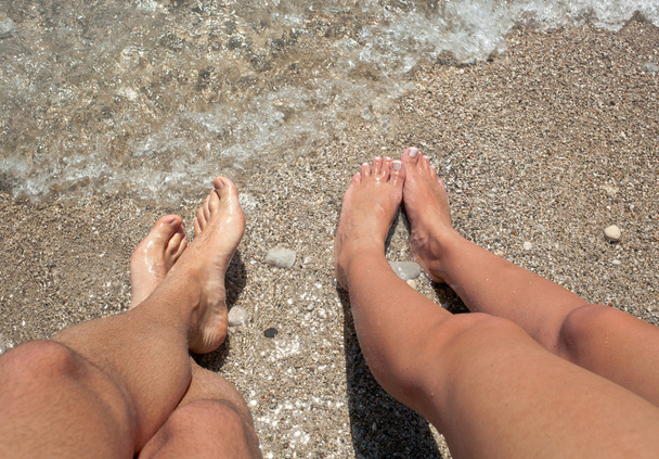 poten van een man en een vrouw met haar voeten in de zee - Foto, afbeelding