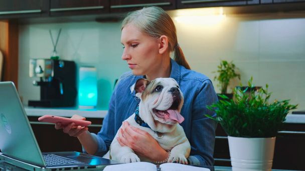 Caucasian woman making selfie with a small dog while sitting at the computer - 写真・画像