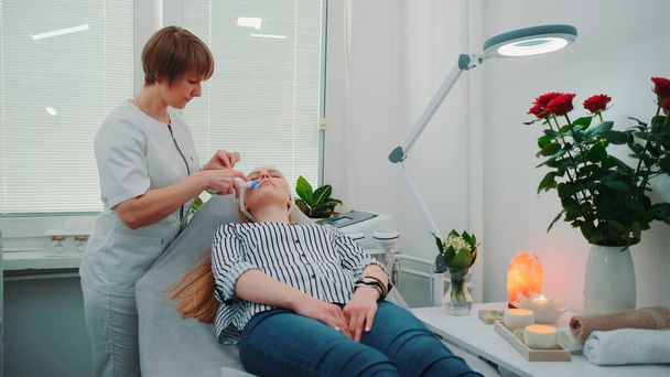 Cosmetólogo profesional haciendo cavitación peeling en la cara de las mujeres jóvenes - Foto, imagen