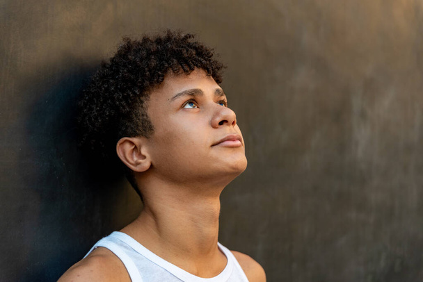Afro latynoski mężczyzna nastolatek pod ścianą, patrząc w górę. - Zdjęcie, obraz