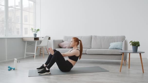 Спортивная женщина делает сидячие упражнения сгибание мышц живота упражнения дома - Кадры, видео
