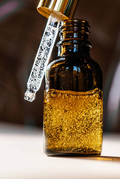 Pipette avec huile cosmétique dans une bouteille brune avec bulles - Photo, image