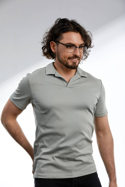 Middle-aged man, stylishly dressed in a gray T-shirt and glasses, business style, smart kezhl, handsome business man with glasses, business style concept, modern approach to mens fashion. - Φωτογραφία, εικόνα