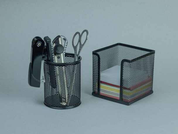 Stapler, stationery knife, scissors in a pencil holder. Paper blocks in a stand. - Photo, Image