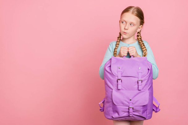 Photo of thoughtful pretty school girl wear blue cardigan holding rucksack looking empty space isolated pink color background - Фото, зображення