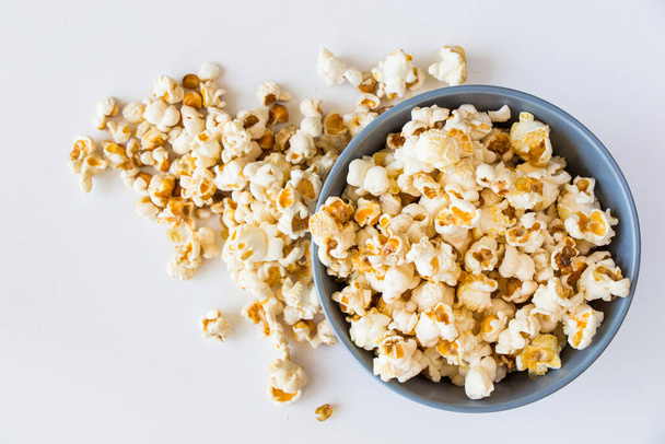Salty popcorn in bowl on the white background, low angle view - 写真・画像