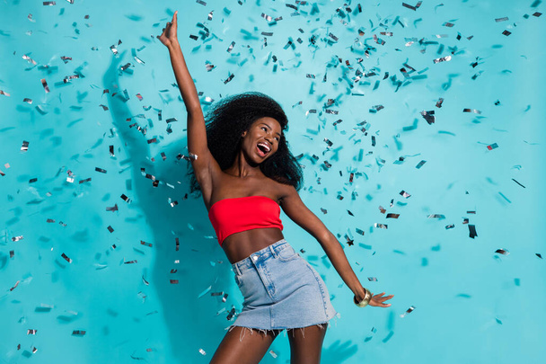 Photo of attractive young dark skin woman dance fall confetti festive party summer isolated on teal color background - Foto, Imagem