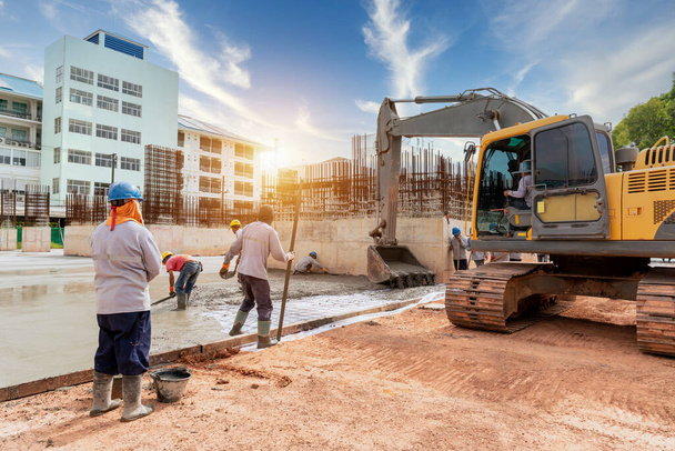 Robotnik budowlany z koparki ciężkiej maszyny i ciężarówki cementu do sterowania pompy betonowej wylewania na placu budowy - Zdjęcie, obraz