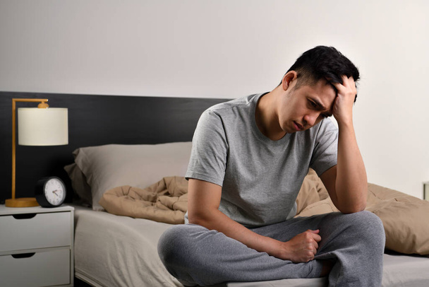 Depressed young Asian man sitting in bed cannot sleep from insomnia - Foto, immagini