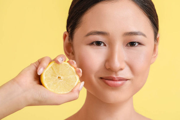 Young woman with lemon on color background - Photo, Image