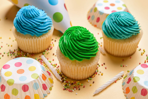 Композиція зі смачними кексами на день народження, вечірній капелюх та свічки на кольоровому фоні, крупним планом
 - Фото, зображення