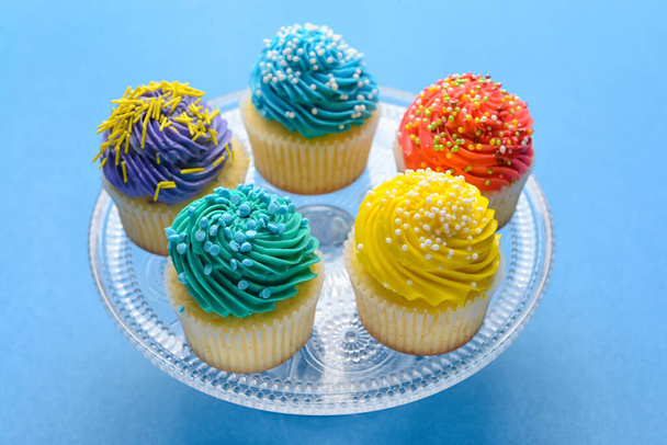 Stand con sabrosos cupcakes de cumpleaños sobre fondo de color - Foto, imagen