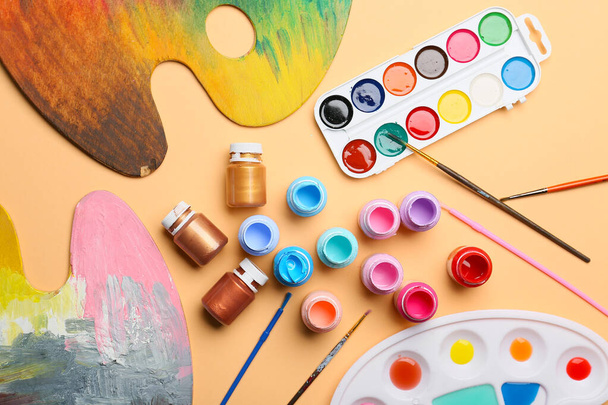 Different paints with brushes on color background - 写真・画像