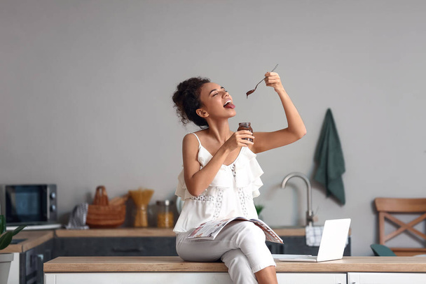 Junge Afroamerikanerin isst Schokopaste in Küche - Foto, Bild
