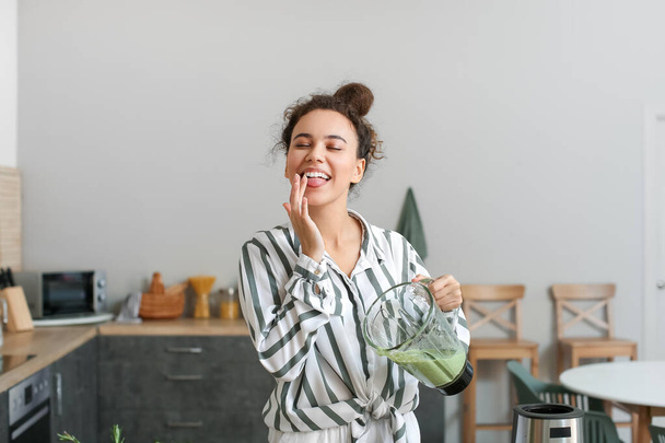 Young African-American woman with fresh smoothie in kitchen - Foto, Imagen